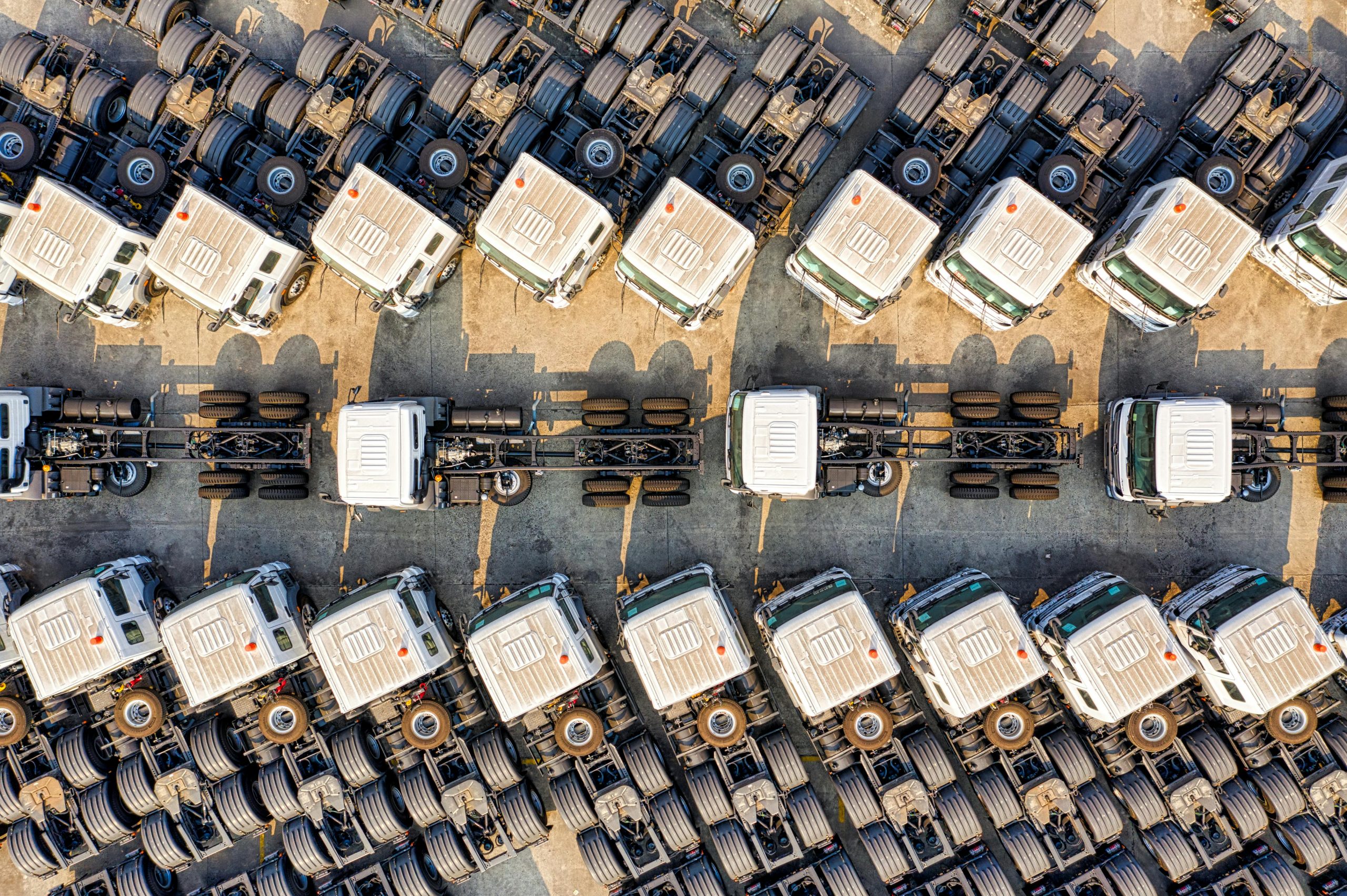 Aerial view of numerous trucks parked neatly in rows in a Jakarta depot, showcasing transportation logistics.